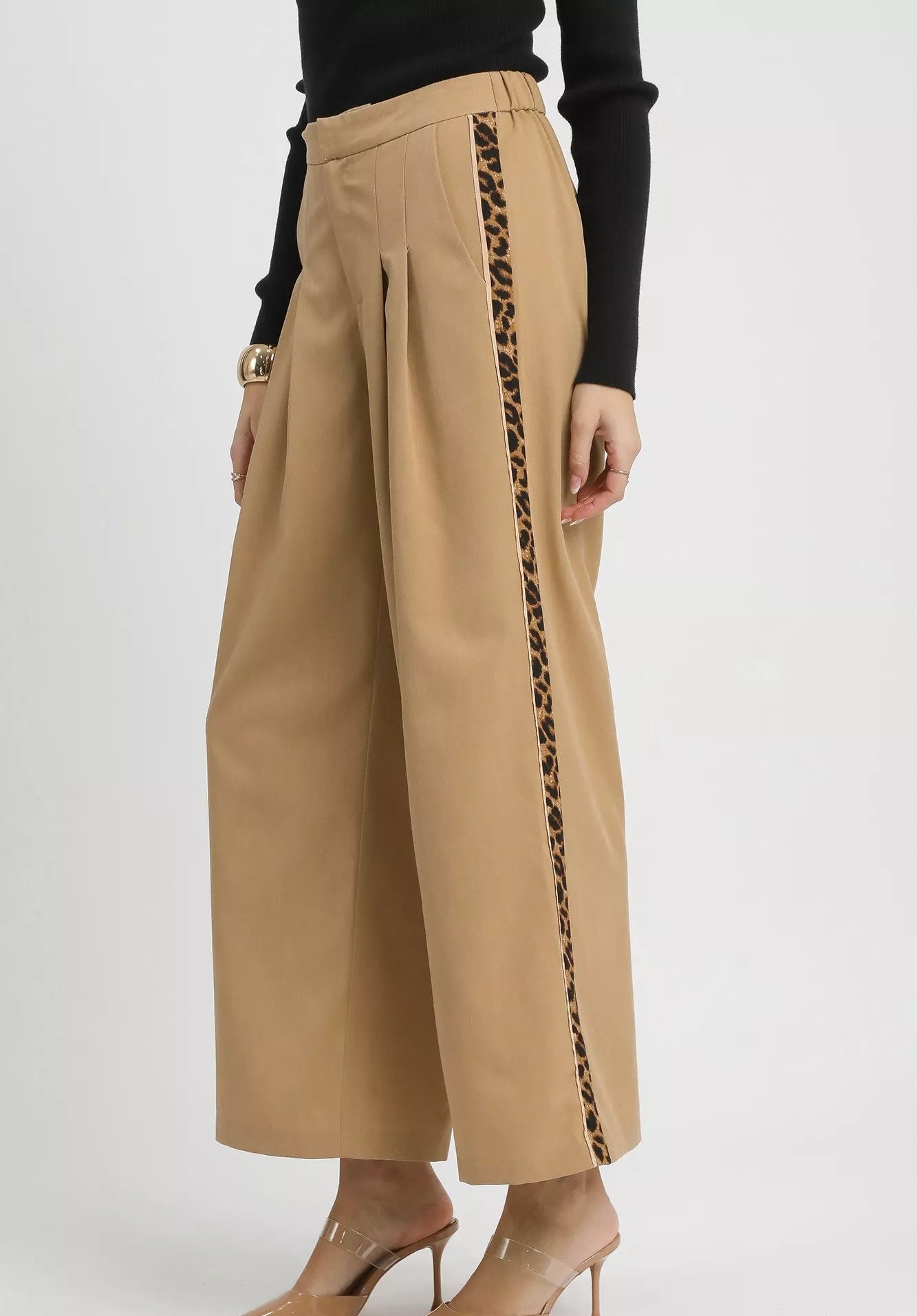 Beige wide-leg pants with leopard print side panels worn by a person on a white background.