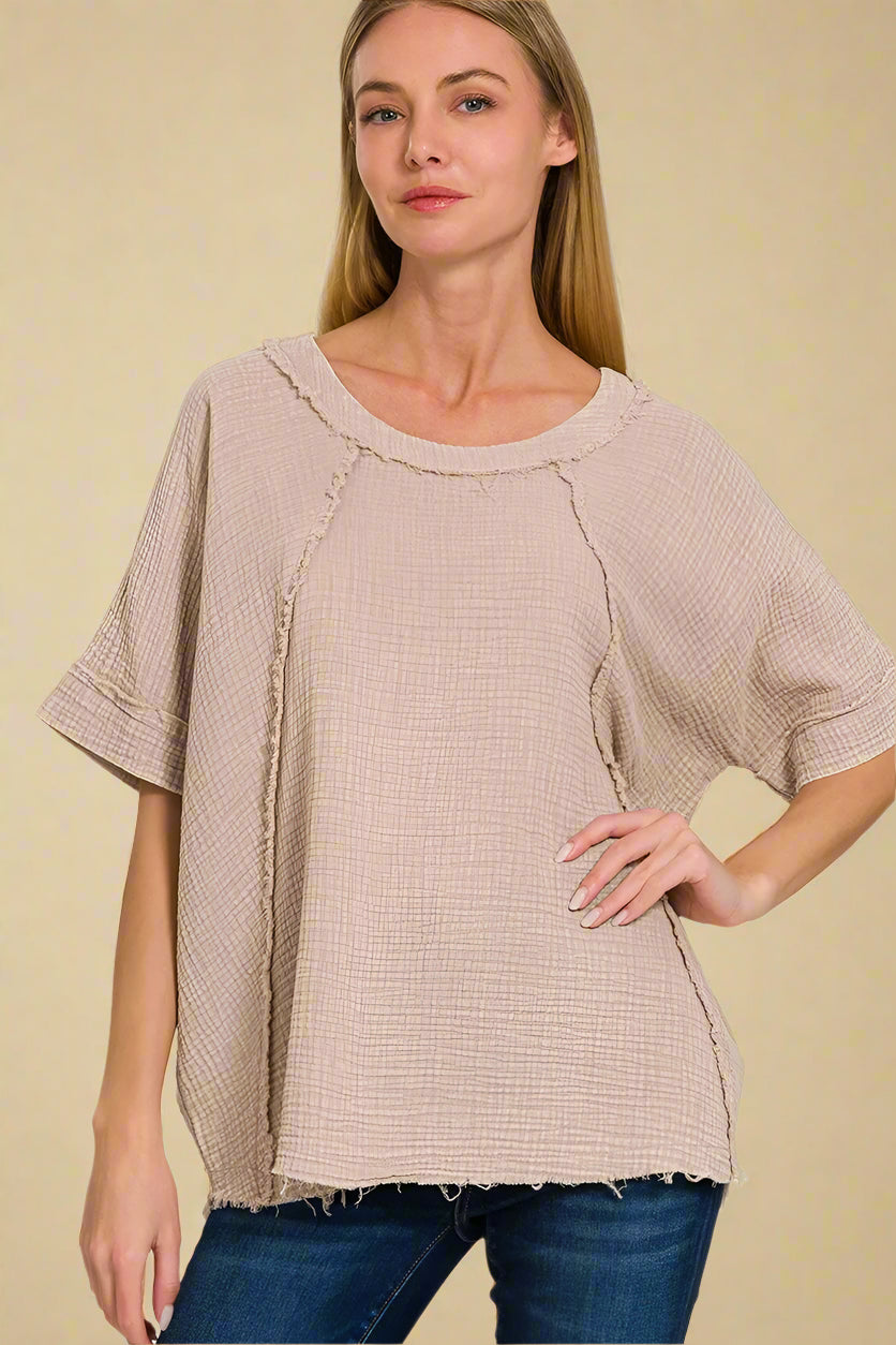 Woman wearing an ash mocha top with a plain background