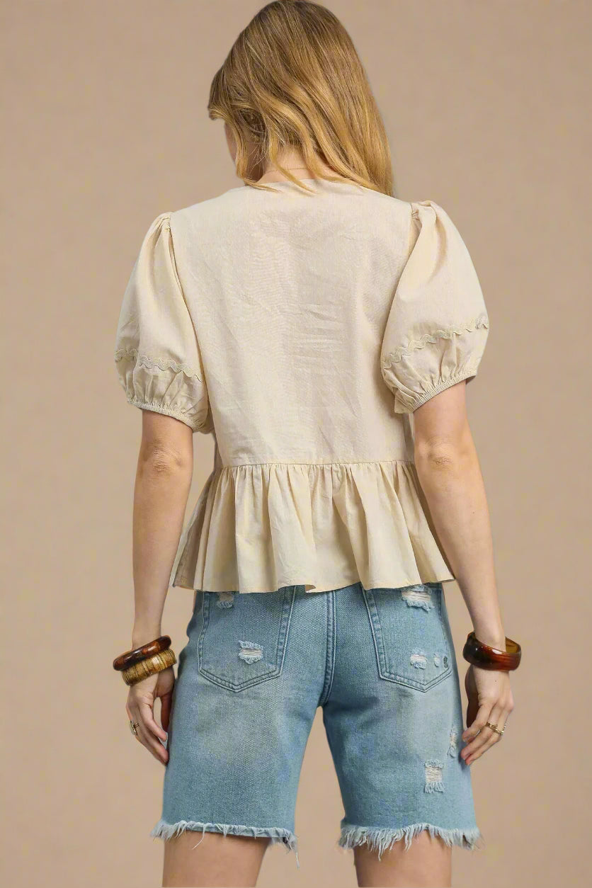 Woman wearing a beige blouse and denim shorts on a beige background