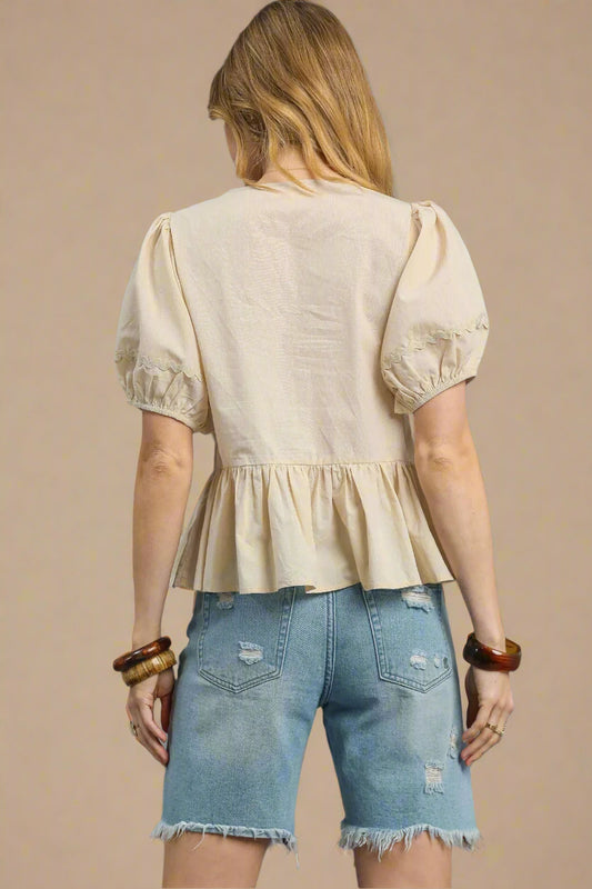 Woman wearing a beige blouse and denim shorts on a beige background