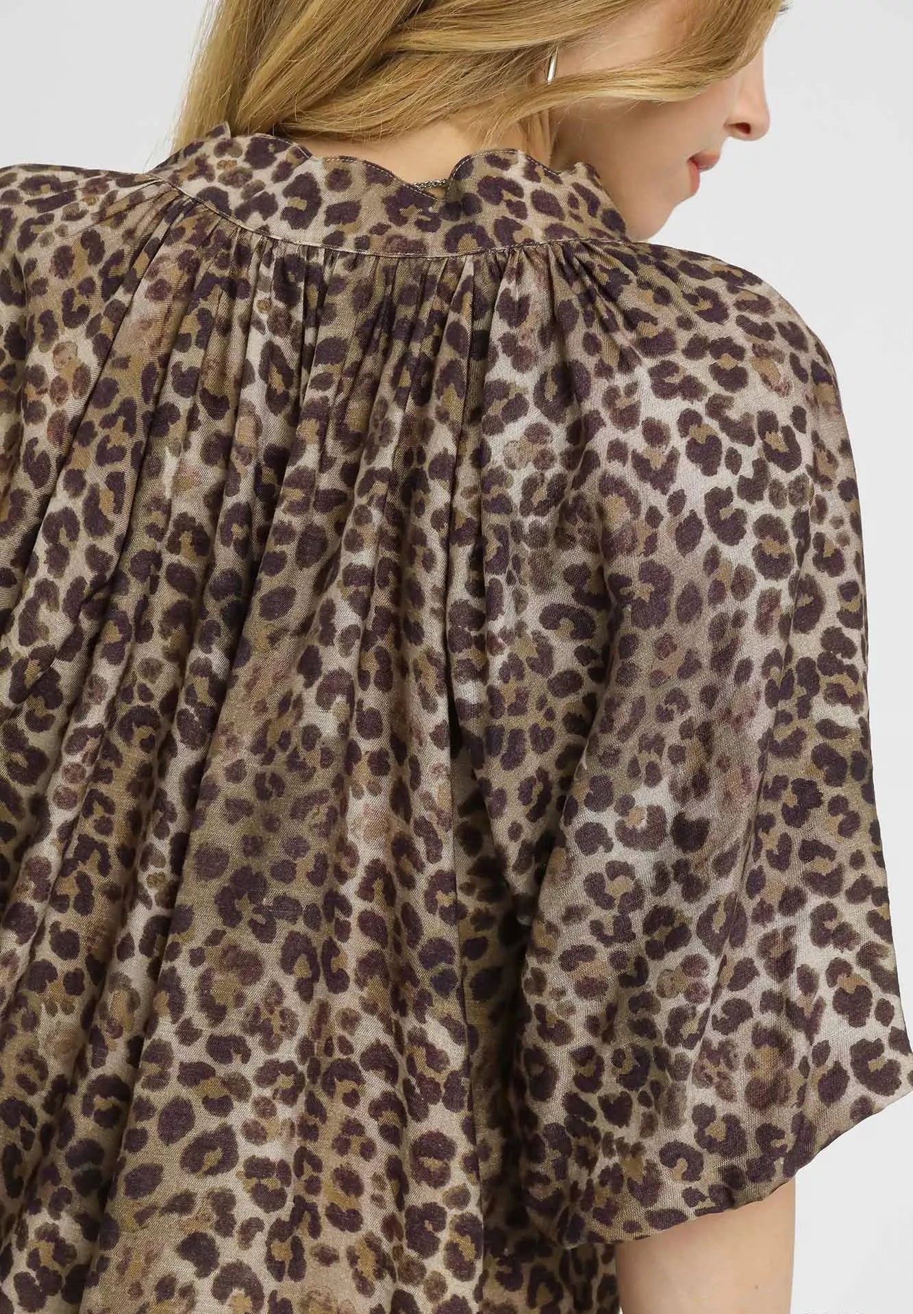 Leopard print blouse worn by a person on a white background