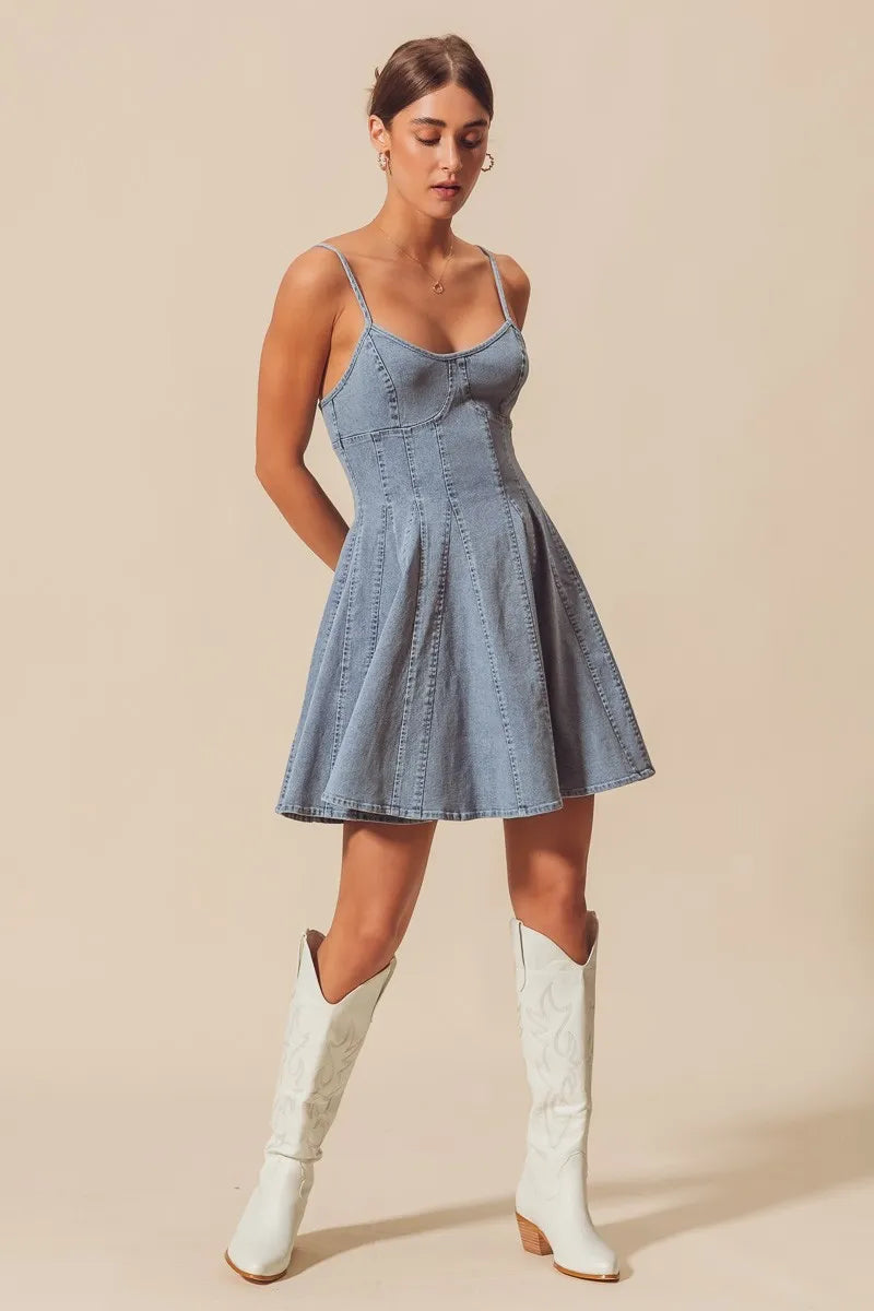 Woman wearing a blue dress and white knee-high boots on a beige background