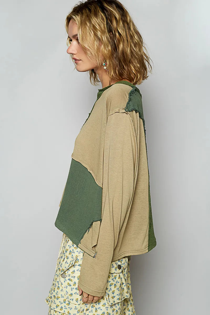 Woman wearing a beige and green color-blocked top with a plain background