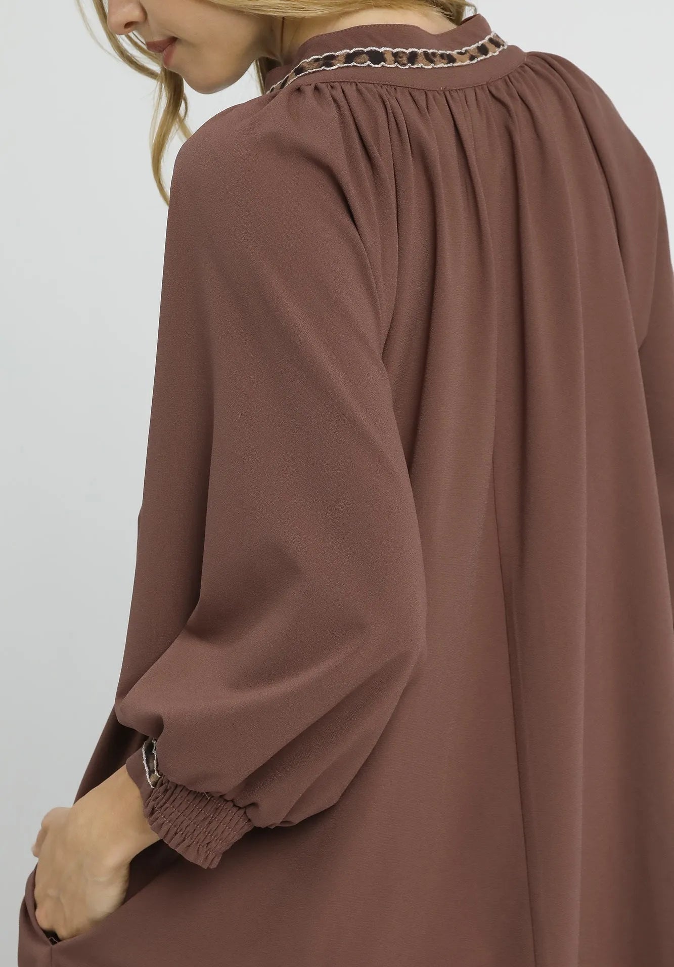 Brown dress with long sleeves and a high neckline on a white background