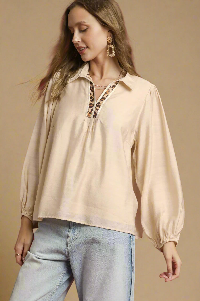 Woman wearing a beige blouse with leopard print accents against a red background