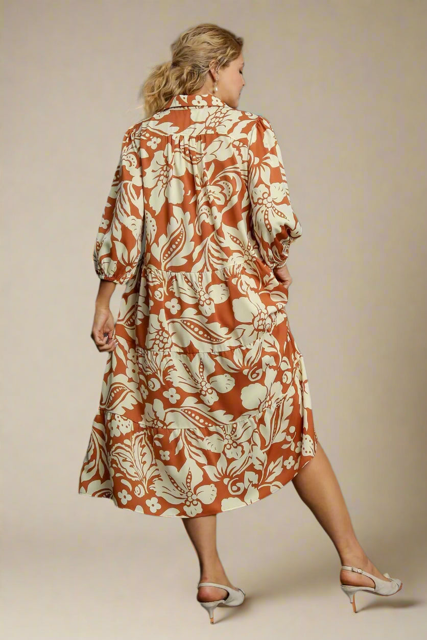 Woman wearing a rust-colored floral dress on a gray background