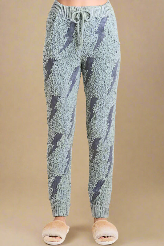Light blue fuzzy jogger pants with dark blue abstract patterns on a beige background