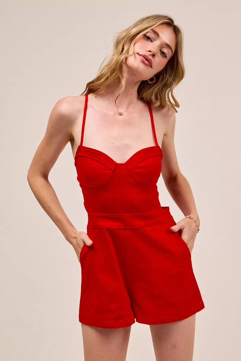 Woman wearing a red romper against a plain background