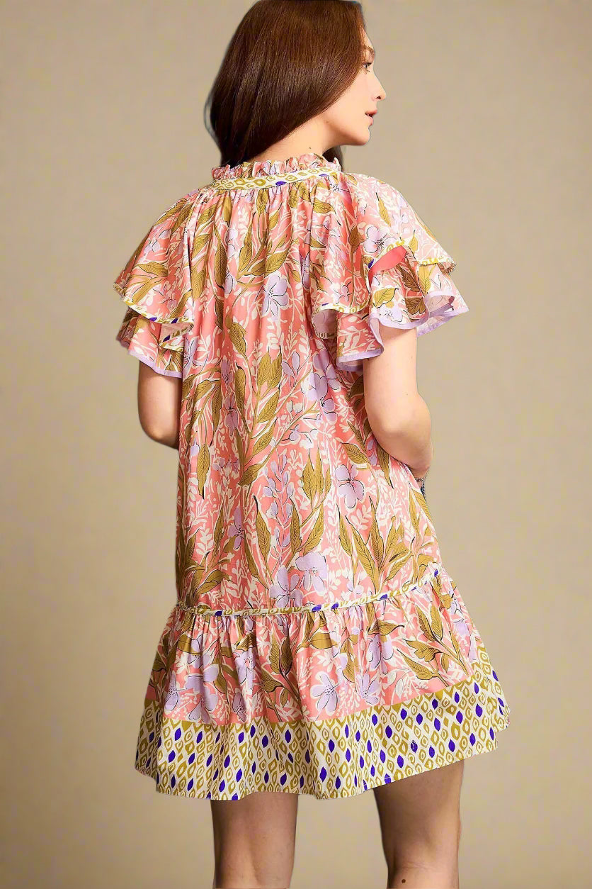 Woman wearing a floral dress with ruffled sleeves against a blue background