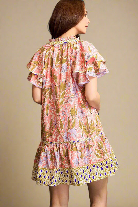 Woman wearing a floral dress with ruffled sleeves against a blue background