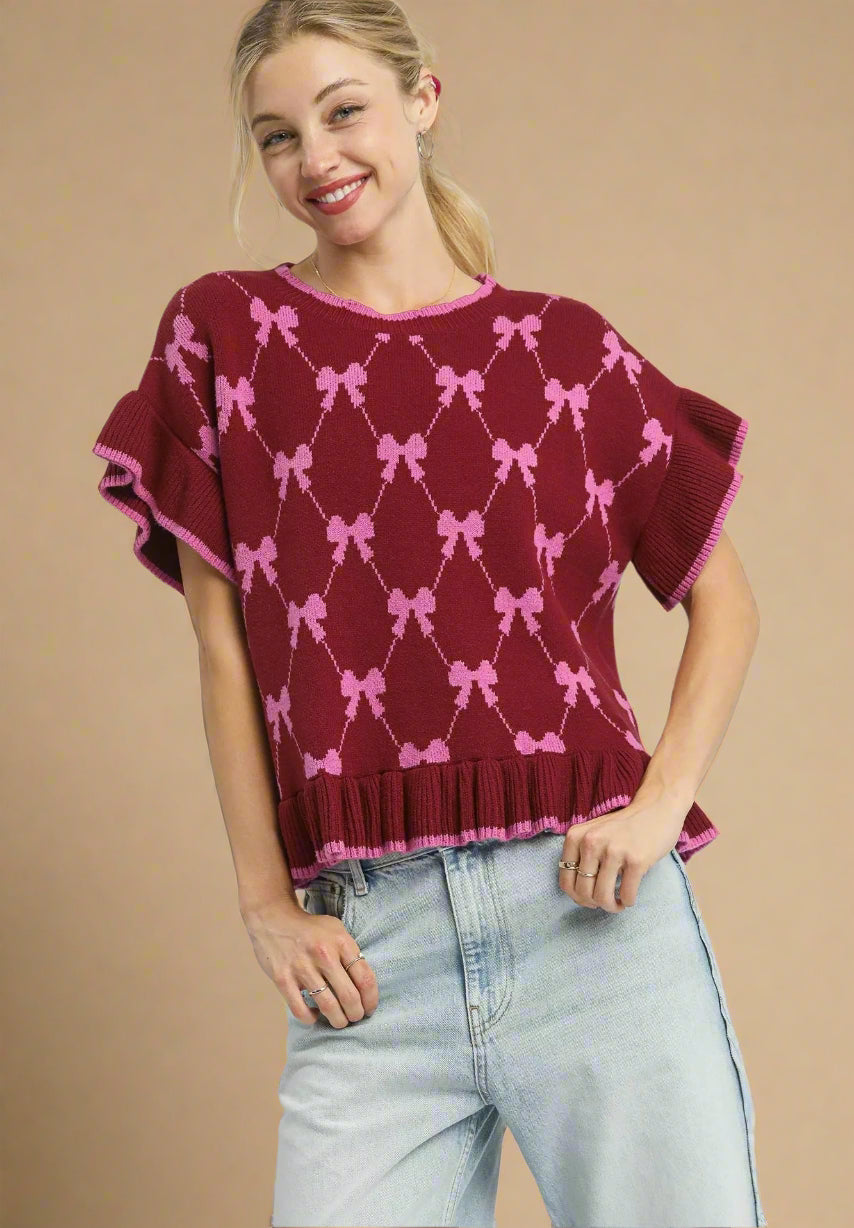 Woman wearing a burgundy sweater with pink bow pattern on a beige background