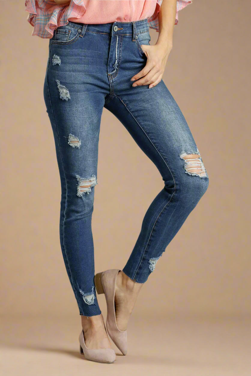 Person wearing distressed denim jeans on a beige background