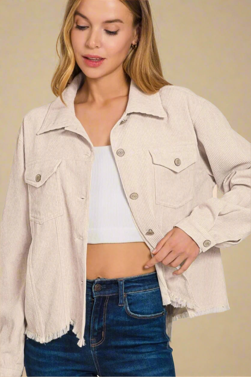Woman wearing a beige jacket over a white top and blue jeans on a white background