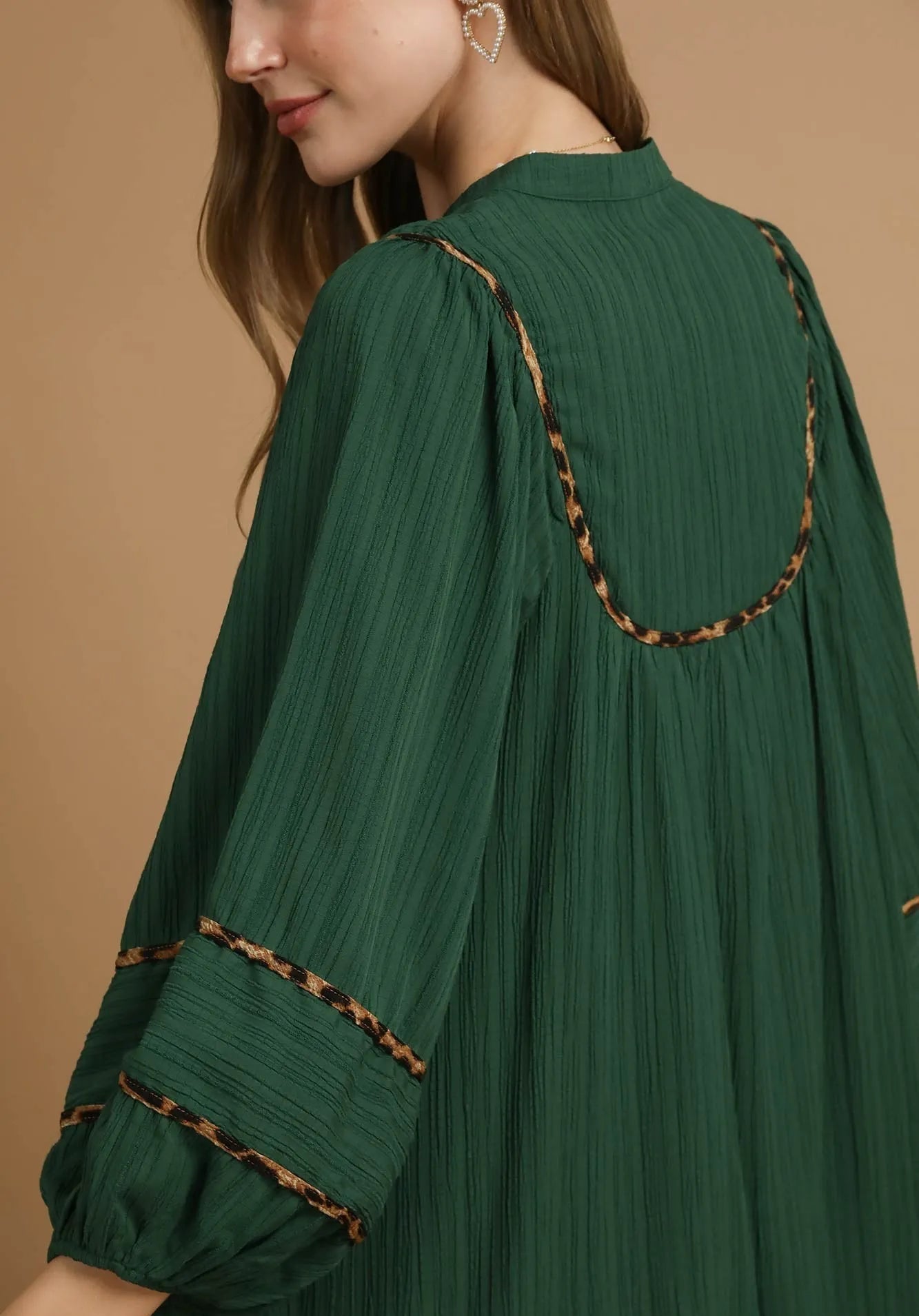 Green dress with brown trim on a beige background