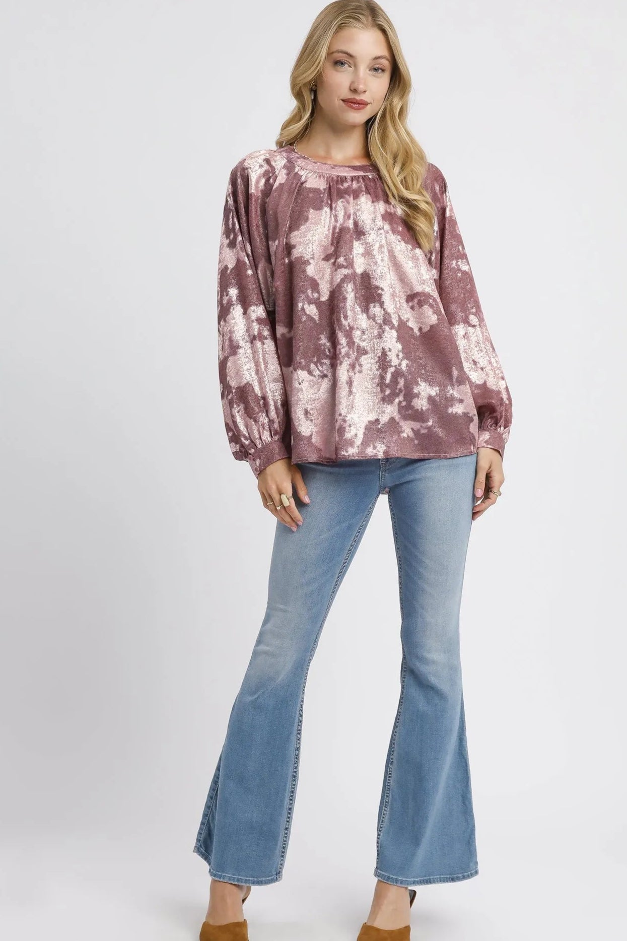 Woman wearing a tie-dye top and blue jeans on a white background