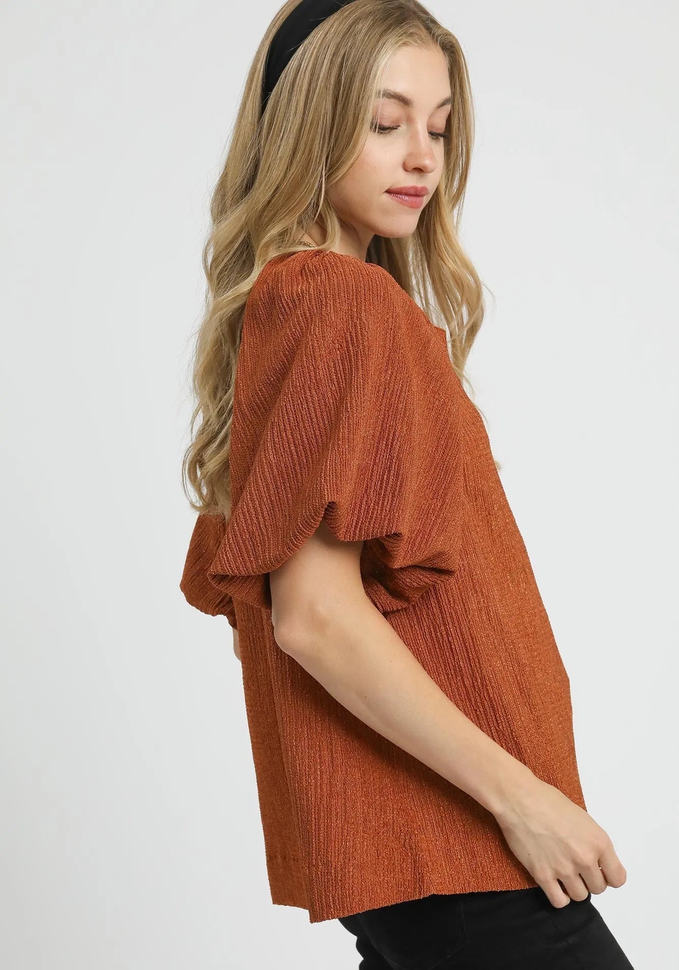 Woman wearing a rust-colored knit top on a white background