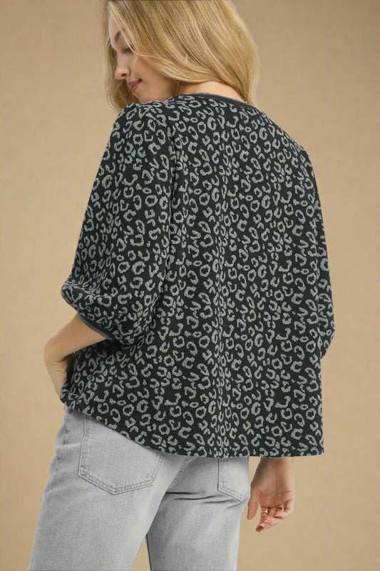 Person wearing a charcoal leopard print shirt with light gray pants on a white background