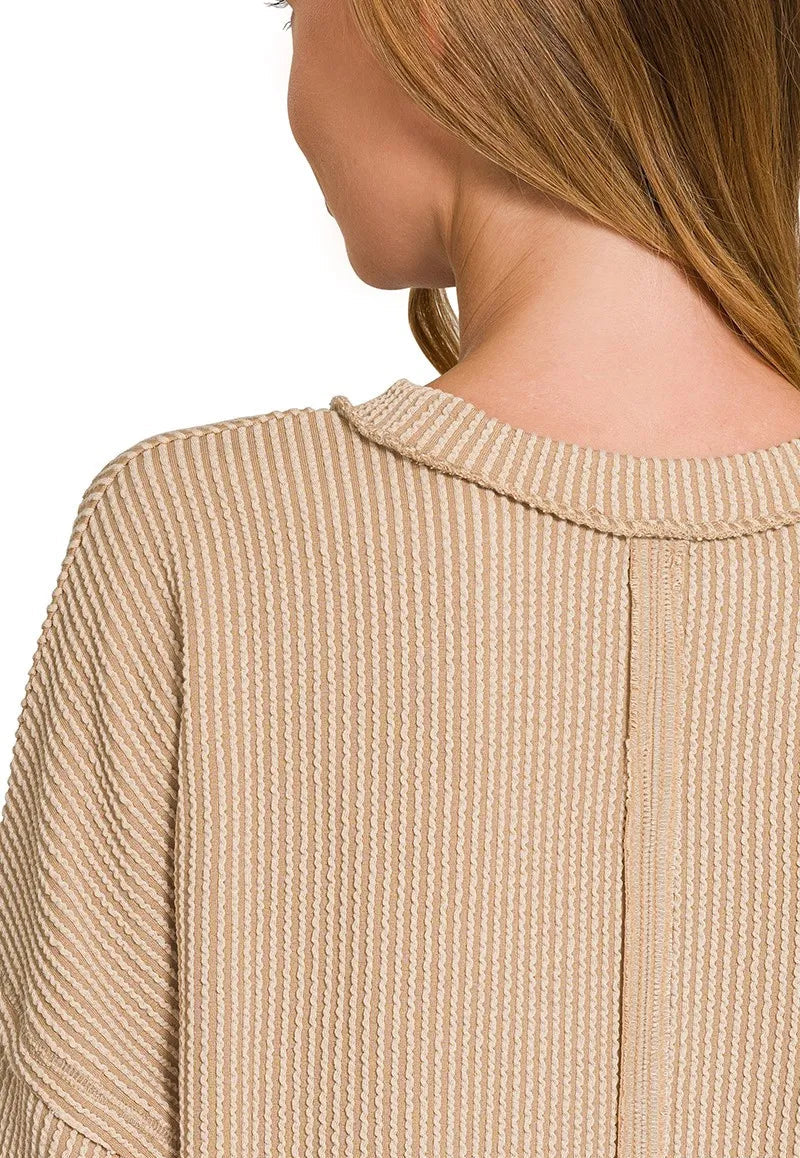 Close-up of a person wearing a light brown textured sweater with a blurred background.