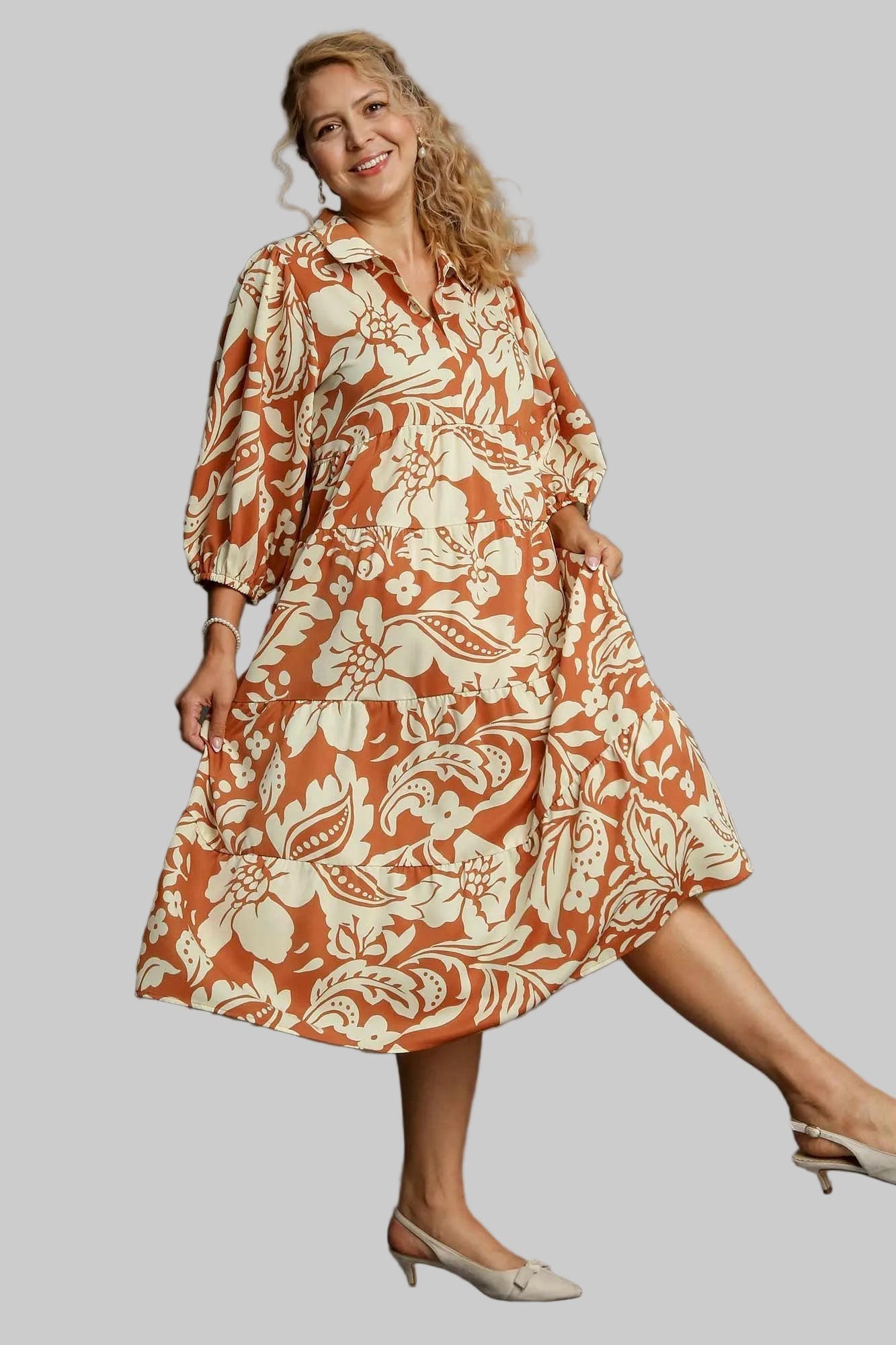 Woman wearing a rust-colored floral dress on a gray background