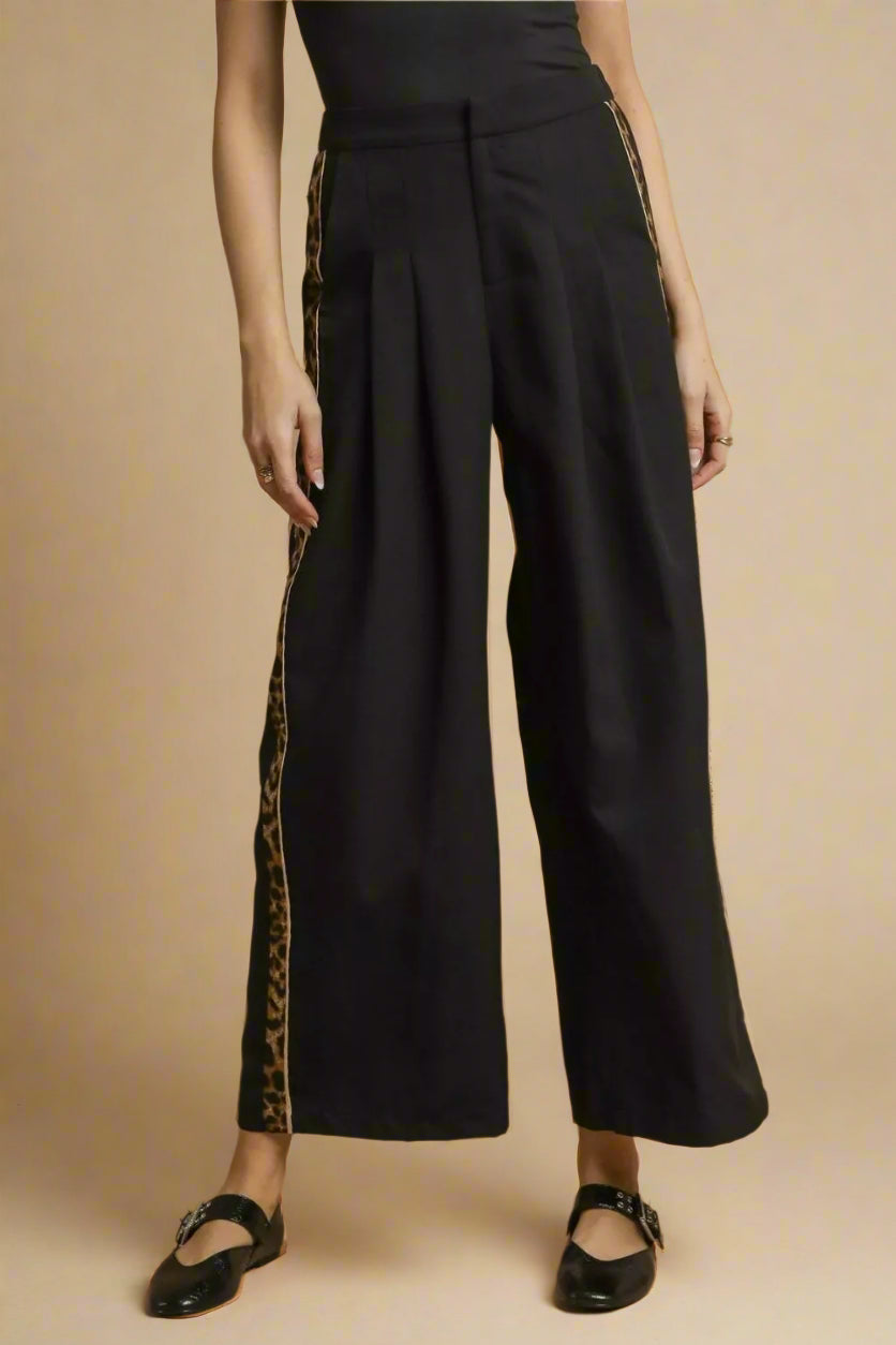 Black wide-leg pants with side stripes on a brown background