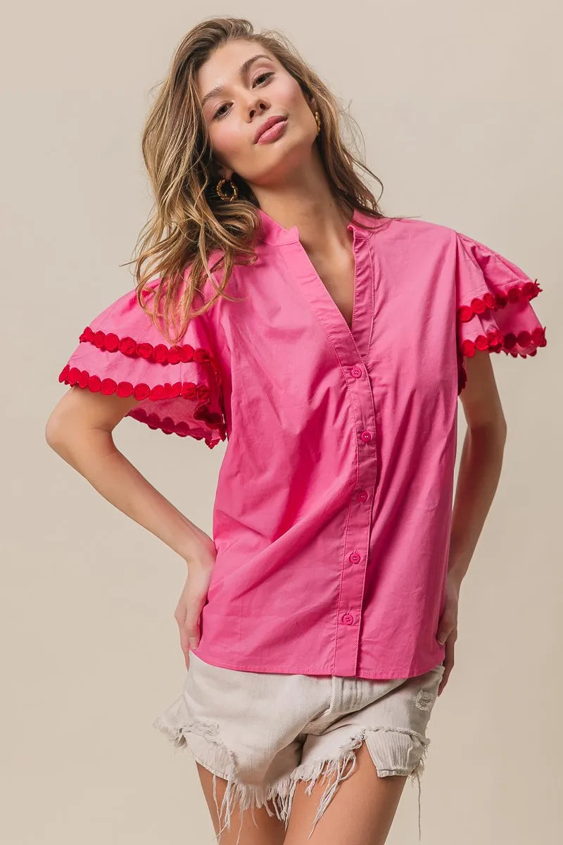Woman wearing a pink blouse with ruffled sleeves on a beige background