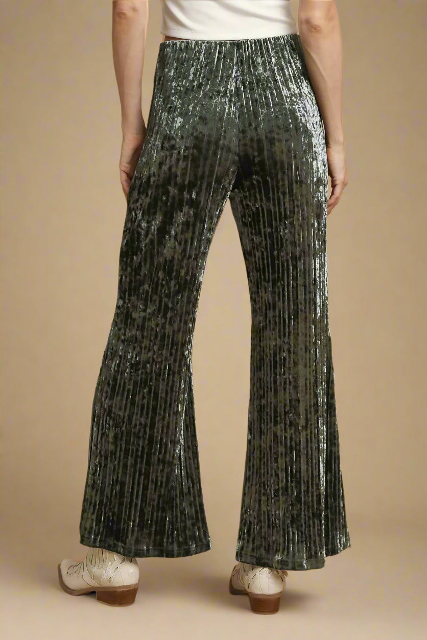 Person wearing olive green pleated pants on a beige background