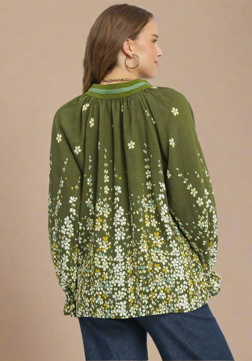 Woman wearing a green floral blouse with long sleeves on a beige background