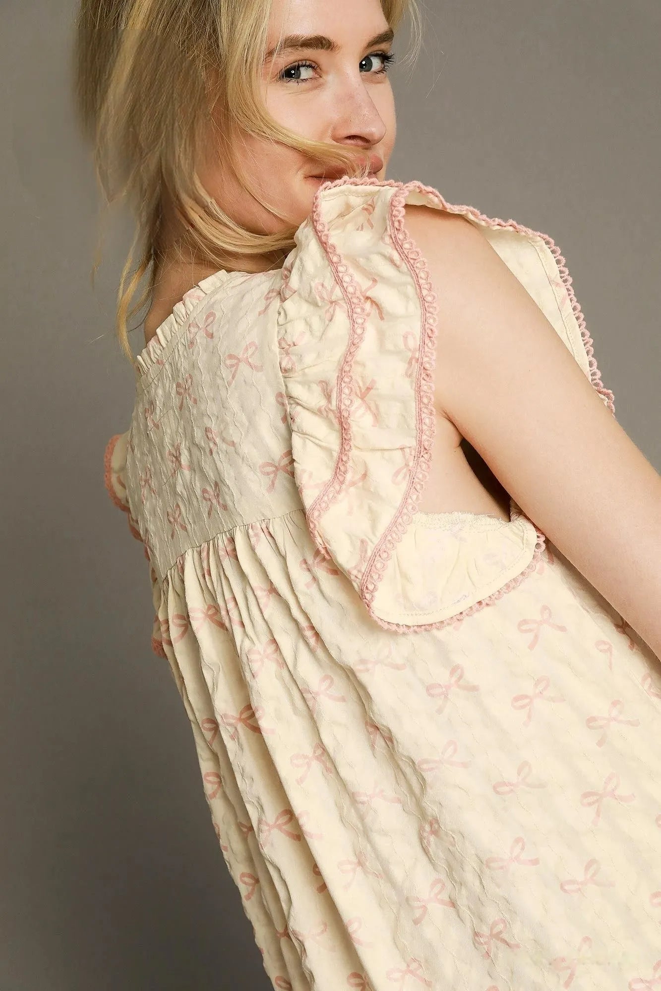 Woman wearing a vintage-style dress with intricate detailing on a plain background