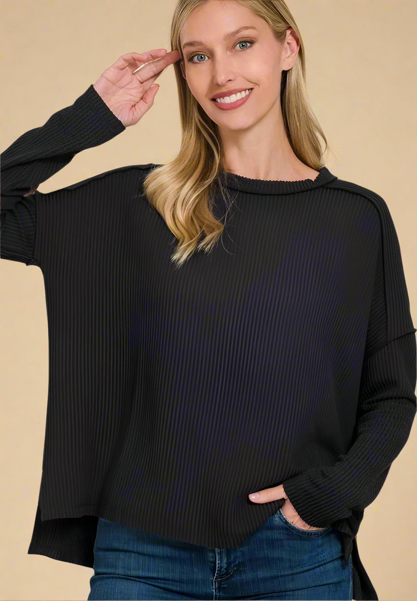 Woman wearing a black sweater and blue jeans on a beige background