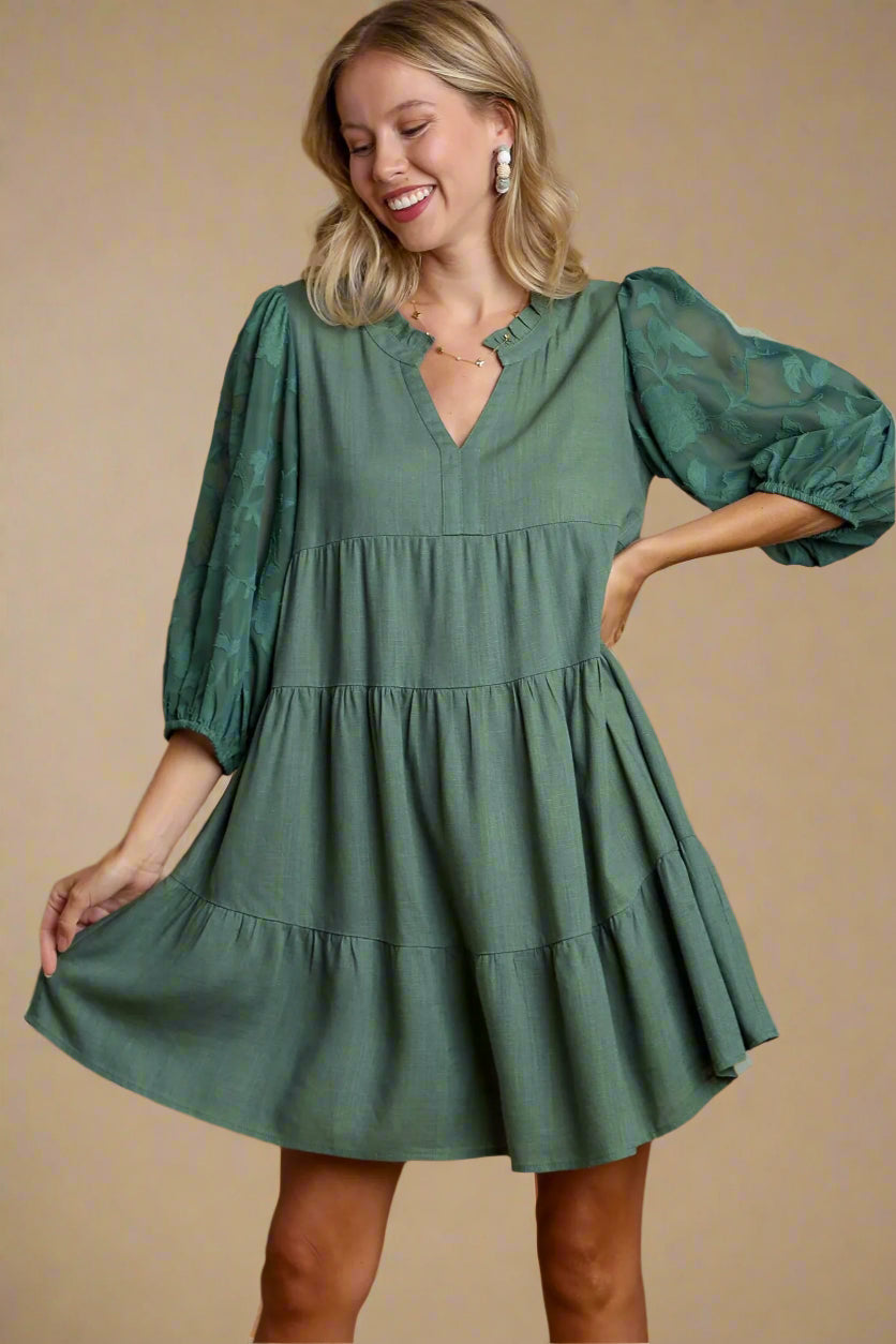 Woman wearing a green dress with puffed sleeves against a beige background