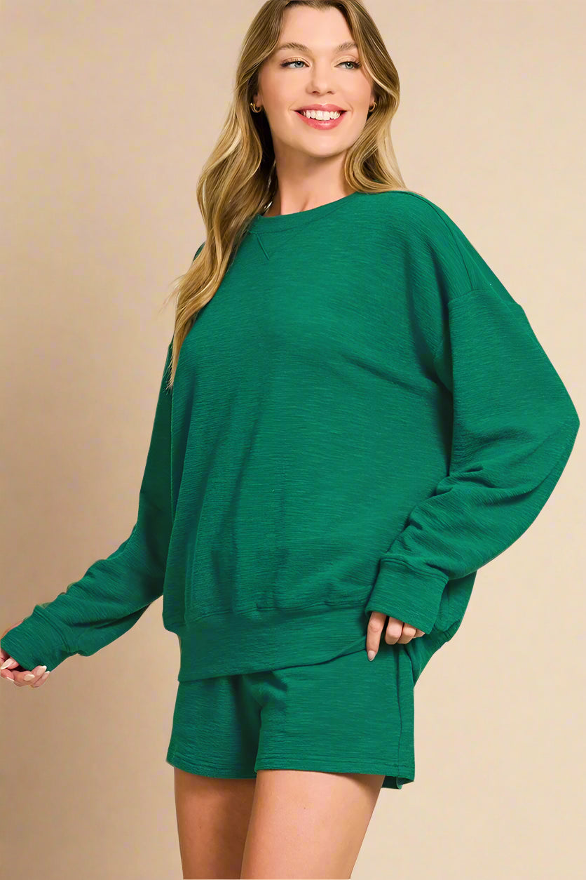 Woman wearing a green sweatshirt and shorts set on a white background