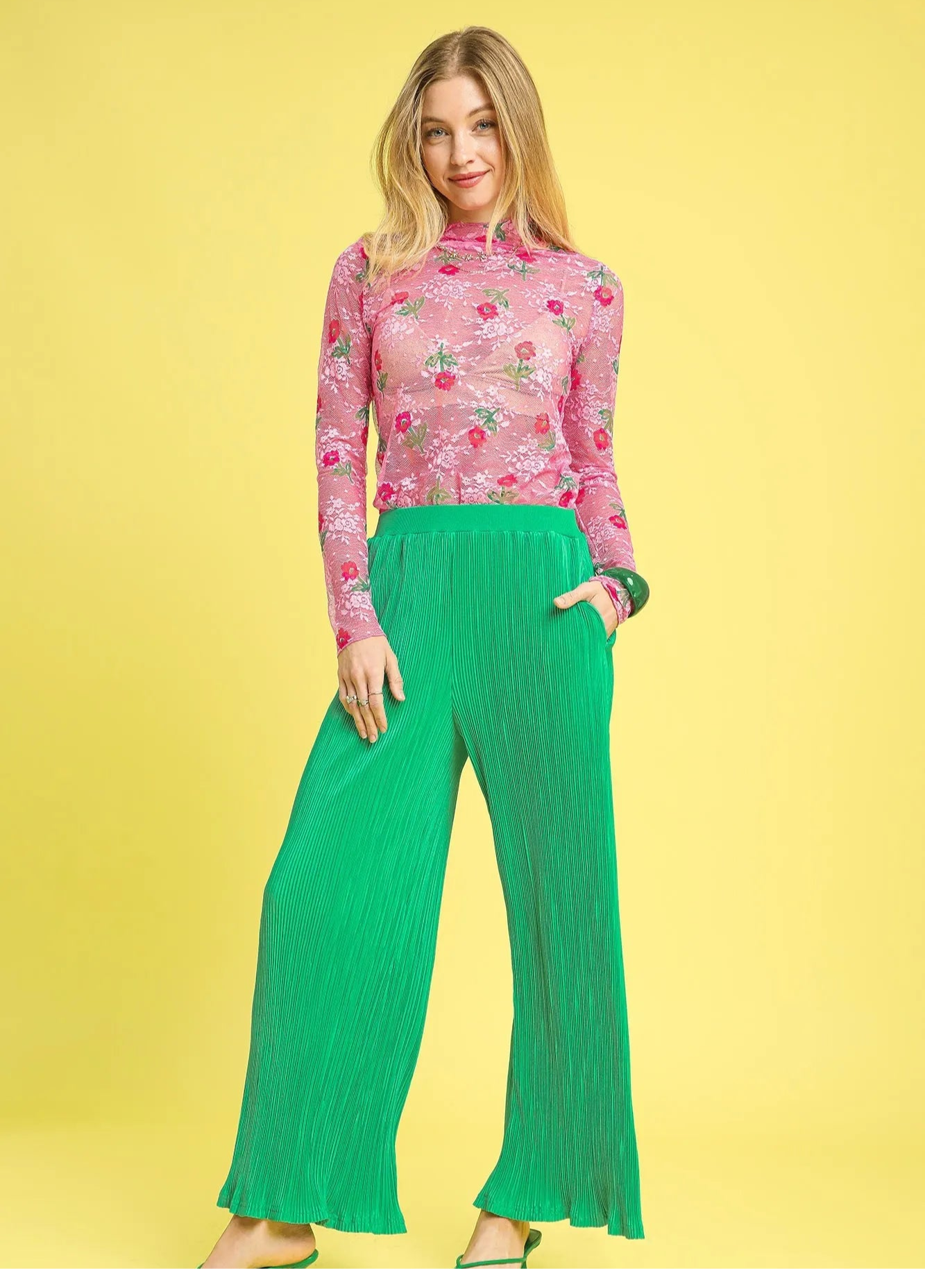Woman wearing a pink floral top and green pants on a yellow background