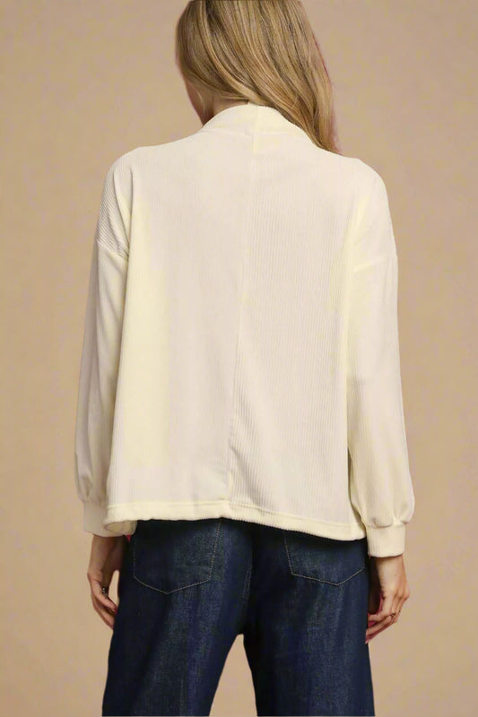 Person wearing a beige blouse and blue jeans against a red background