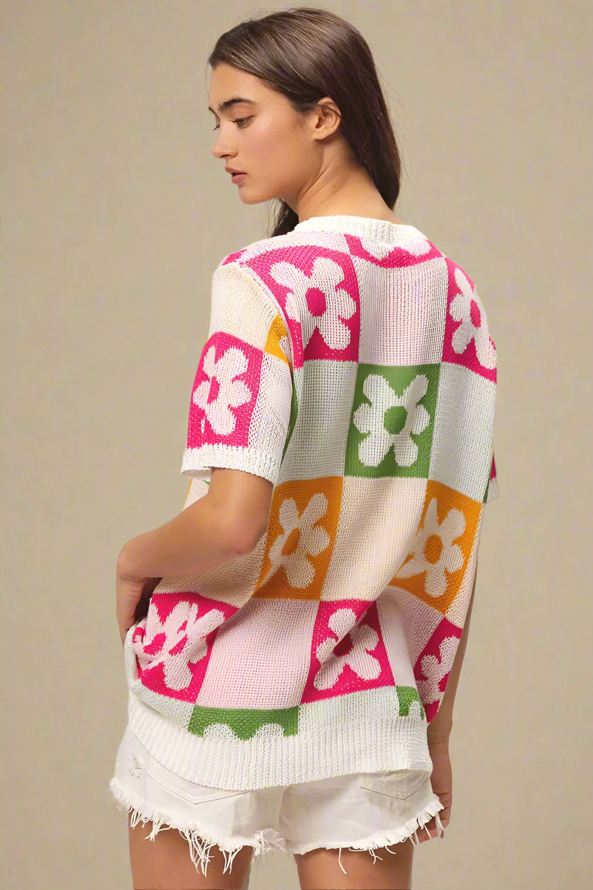 Woman wearing a colorful floral patterned cardigan on a plain background