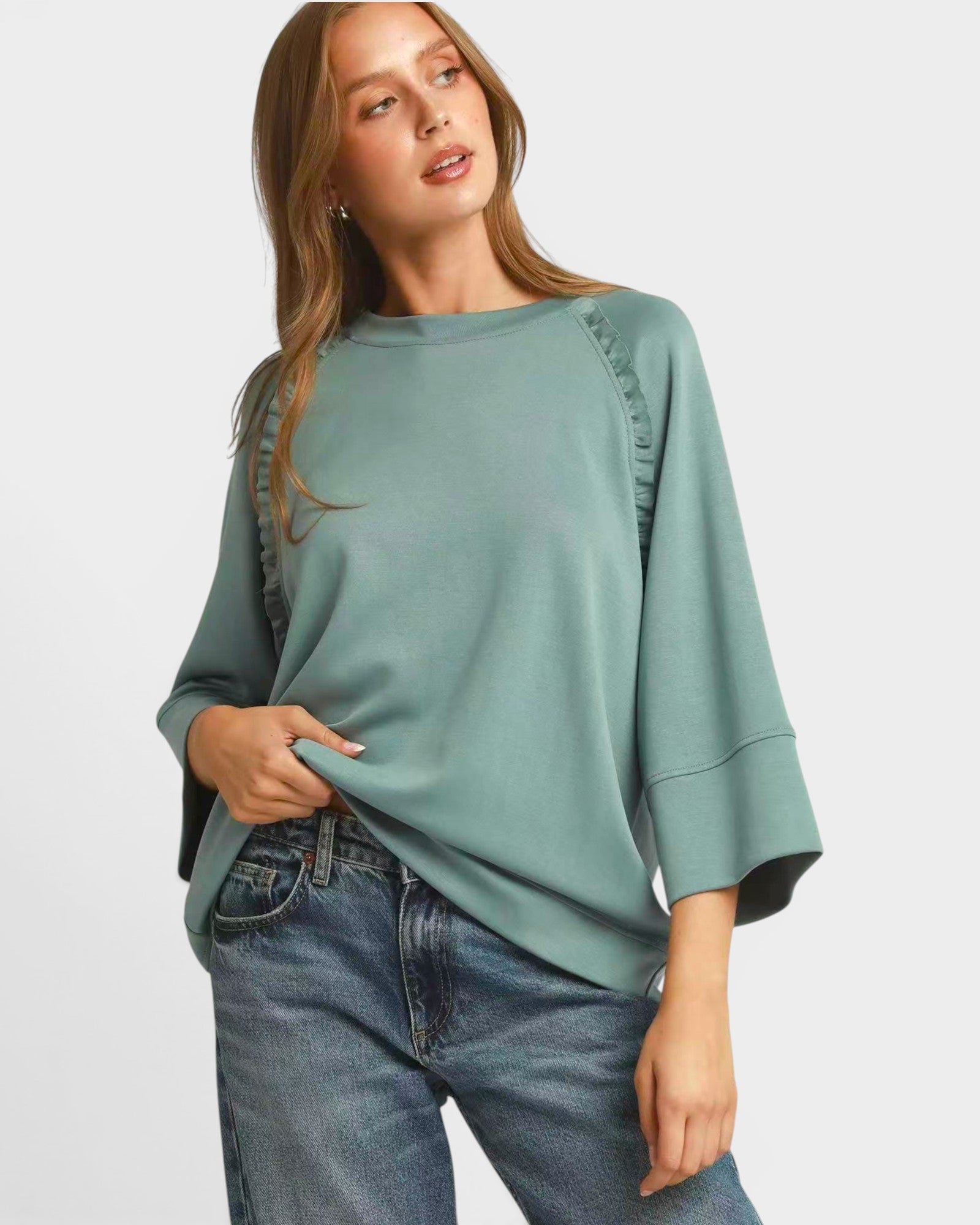 Woman wearing a green sweater and blue jeans on a white background