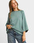 Woman wearing a green sweater and blue jeans on a white background