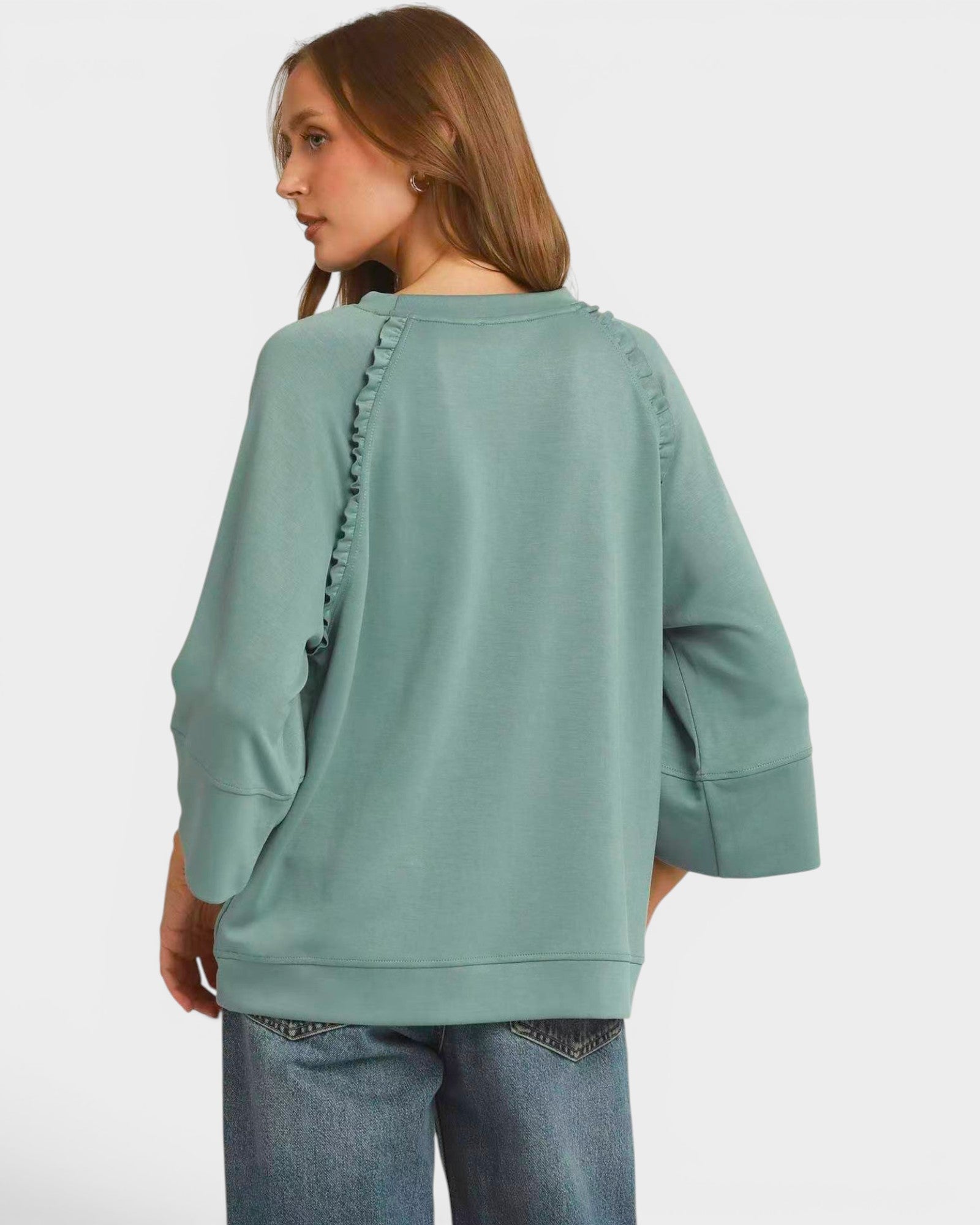 Person wearing a light green sweater with ruched details on a white background
