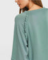 Green long-sleeve top with ruffled details on a plain background