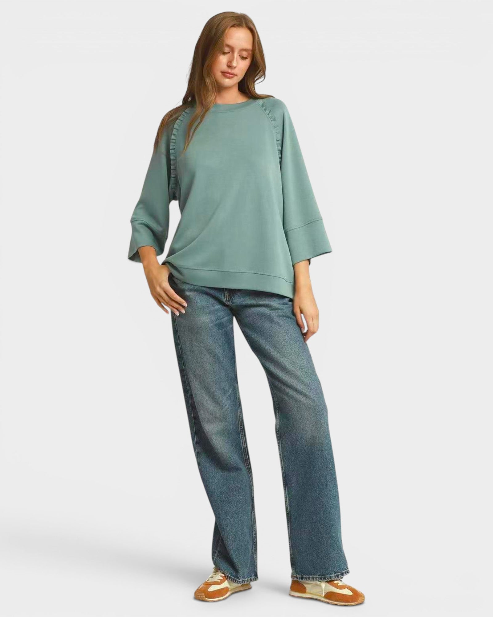 Woman wearing a green top and blue jeans on a white background