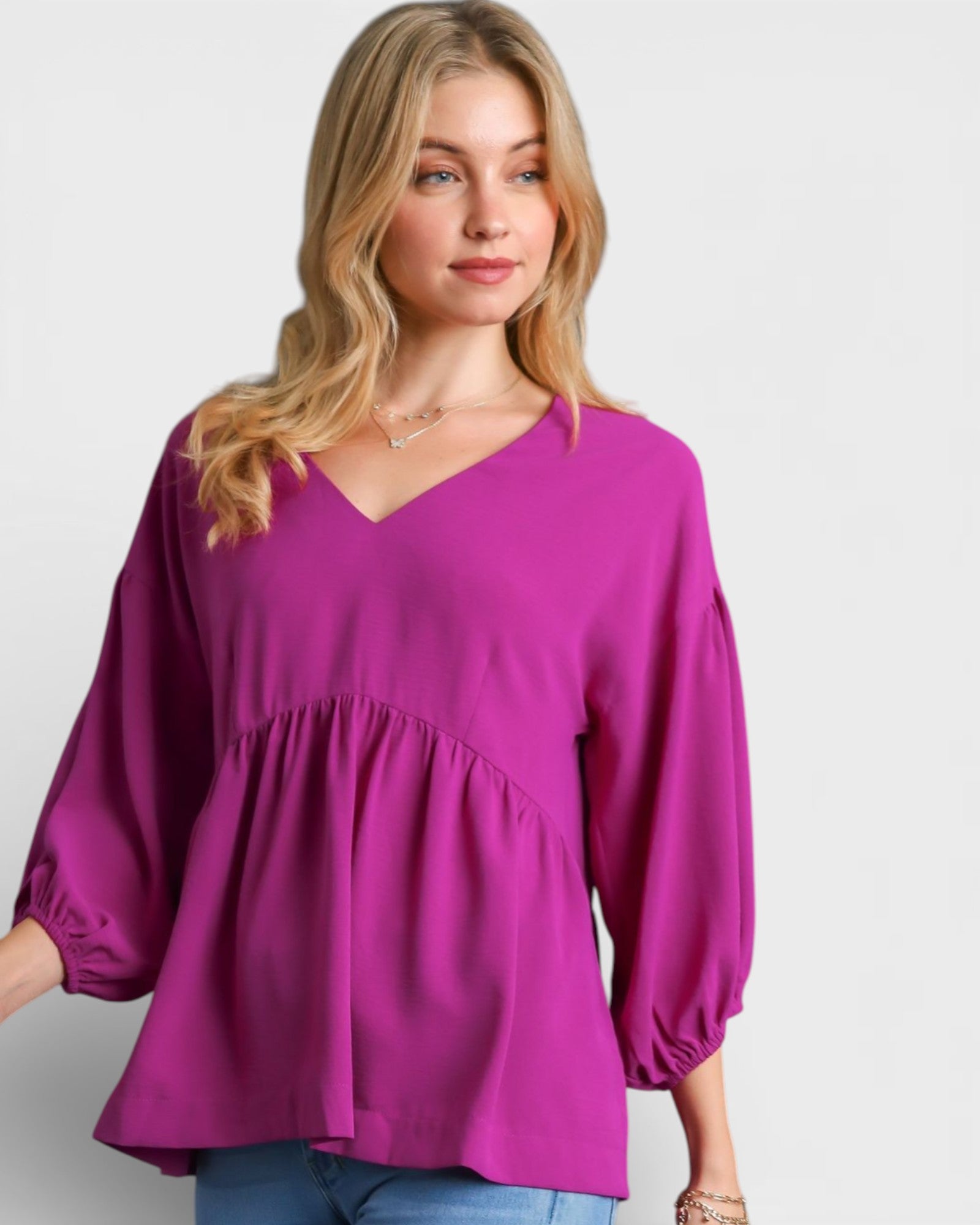 Woman wearing a purple blouse with balloon sleeves on a plain background