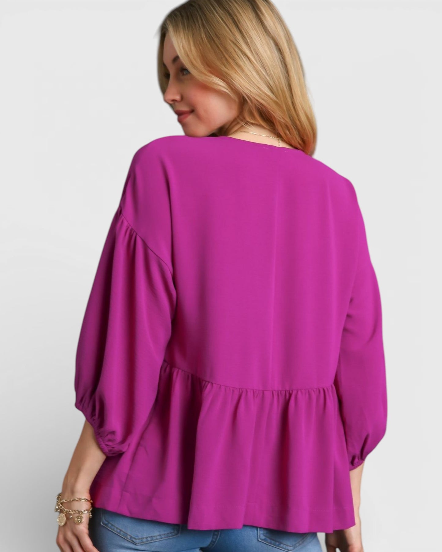 Woman wearing a bright pink blouse with puffed sleeves on a white background