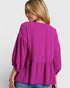 Woman wearing a bright pink blouse with puffed sleeves on a white background