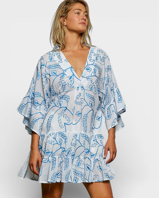 Woman wearing a blue and white patterned dress on a plain background