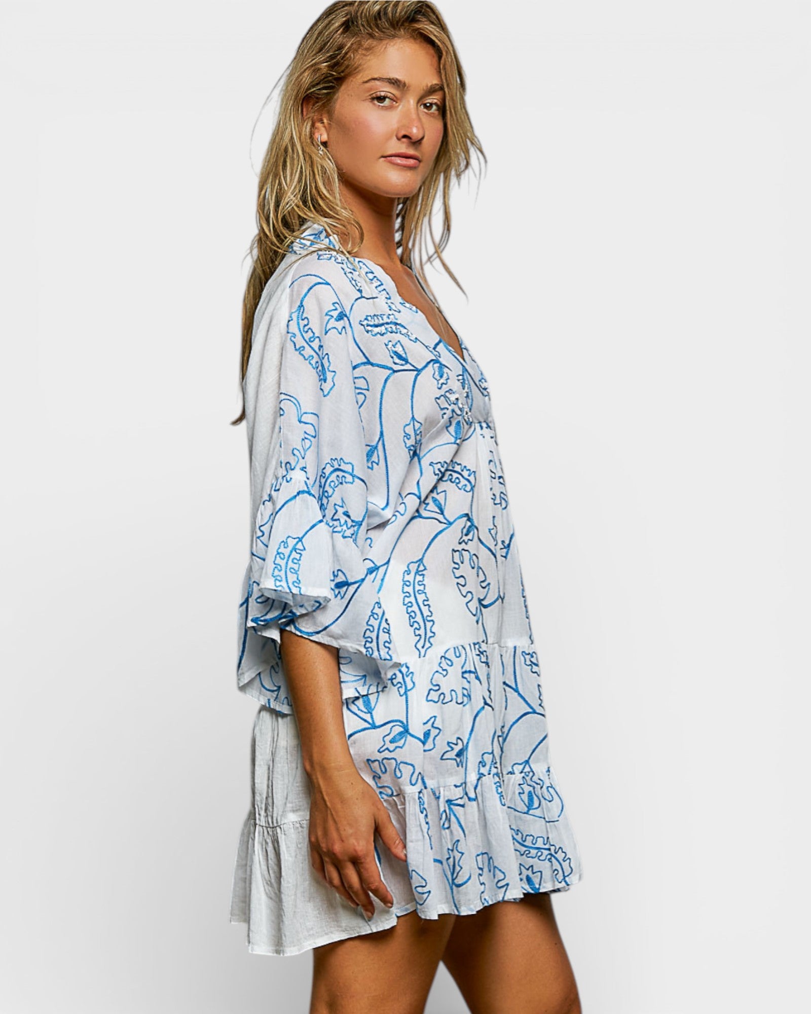 Woman wearing a blue and white patterned dress on a plain background