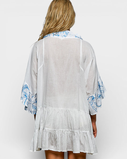 Woman wearing a light gray dress with blue floral patterns on a white background