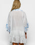 Woman wearing a light gray dress with blue floral patterns on a white background