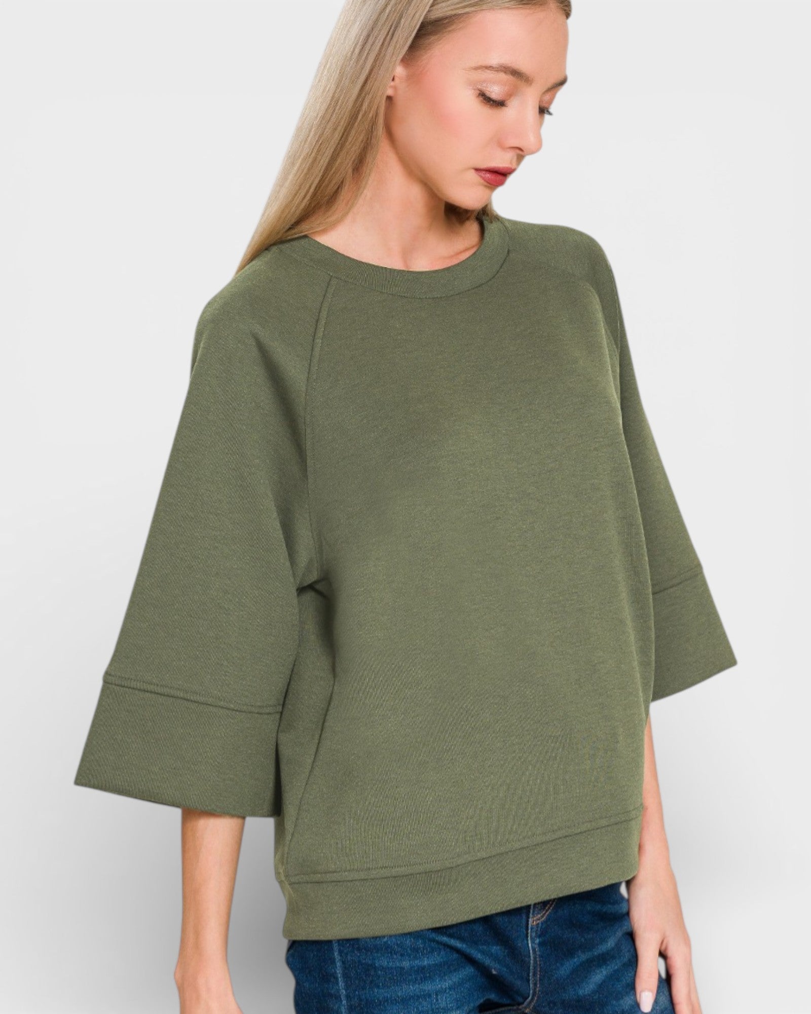 Woman wearing an olive green sweater against a white background