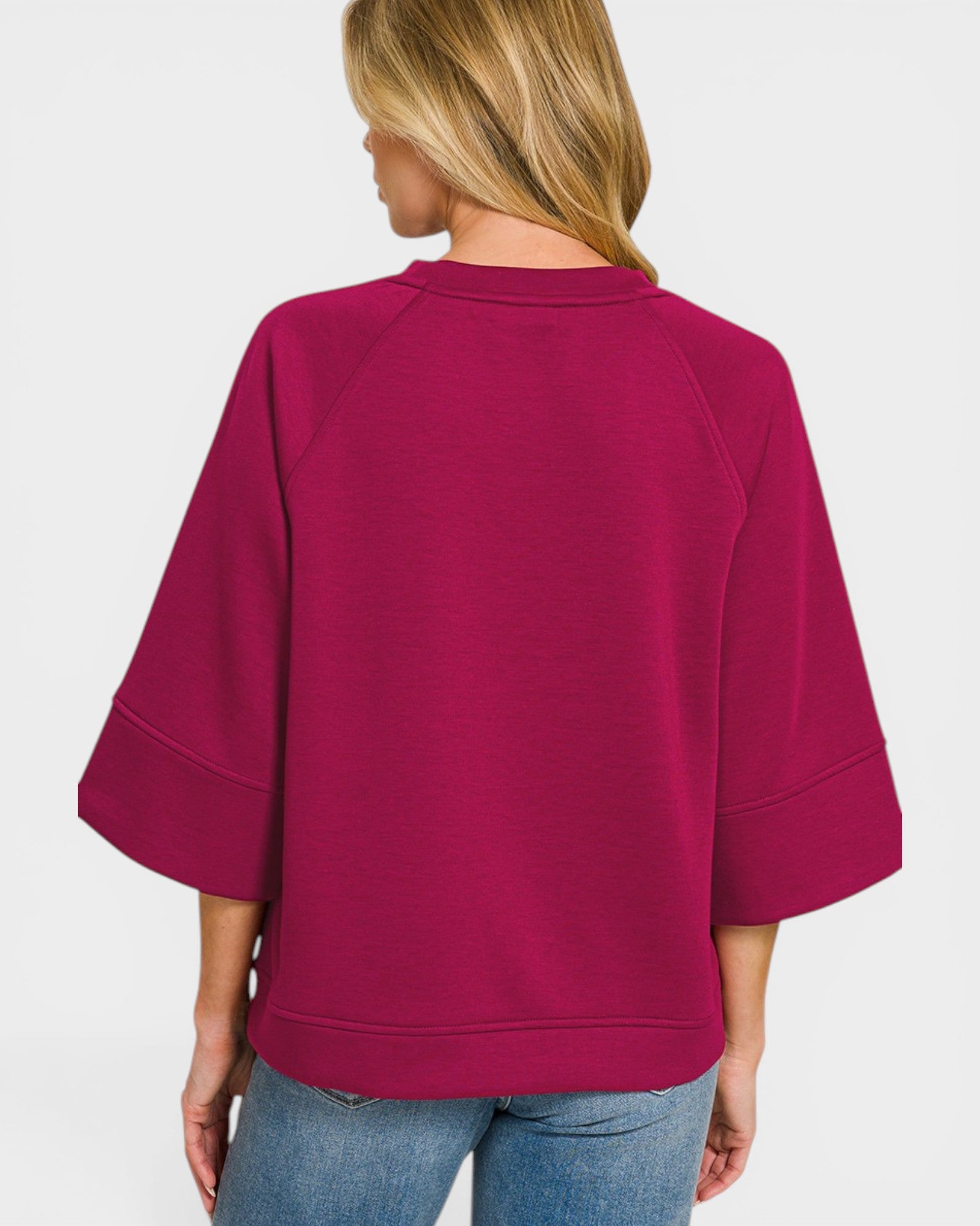 Person wearing a magenta sweater on a plain background
