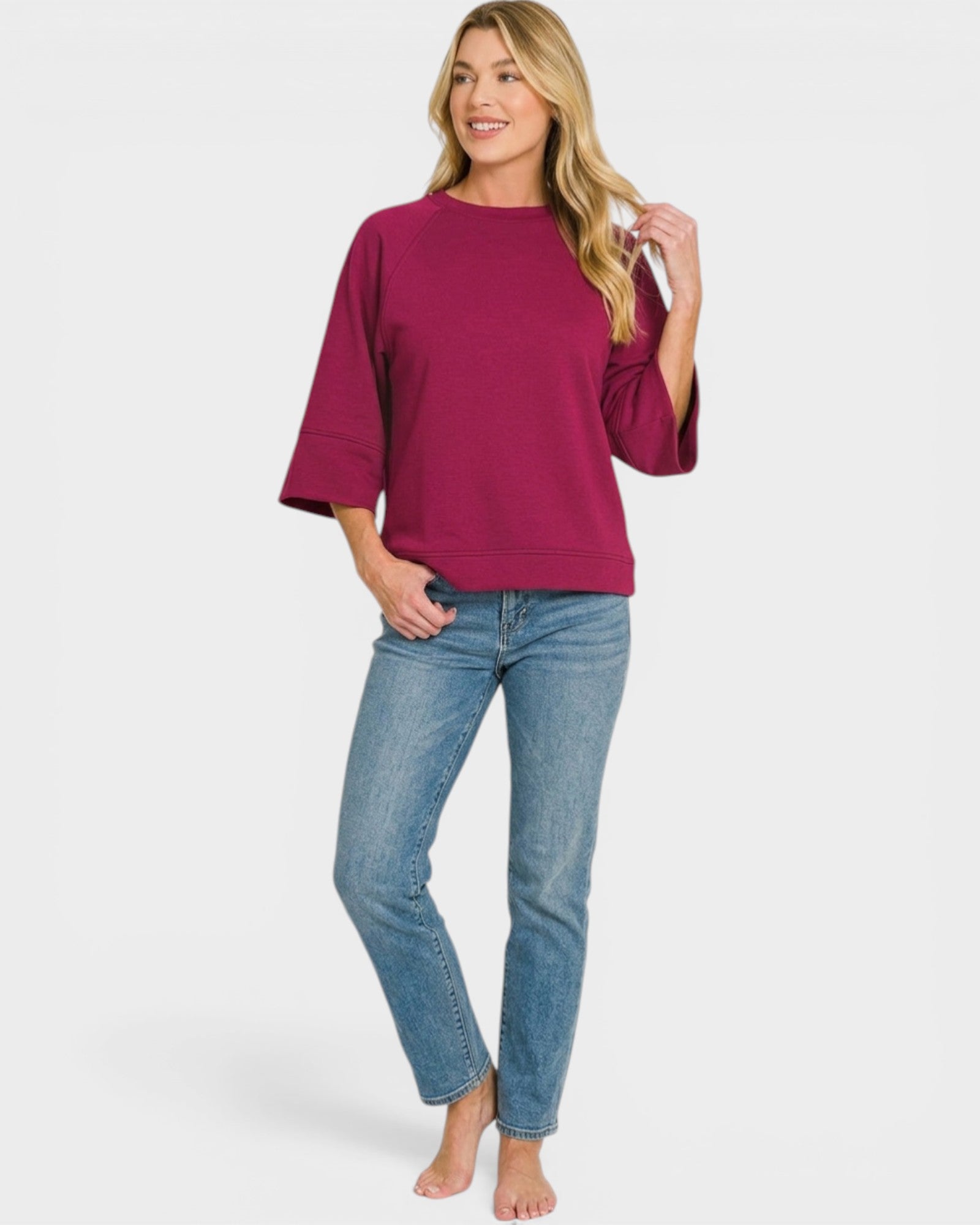 Woman wearing a magenta top and blue jeans on a white background
