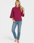 Woman wearing a magenta top and blue jeans on a white background